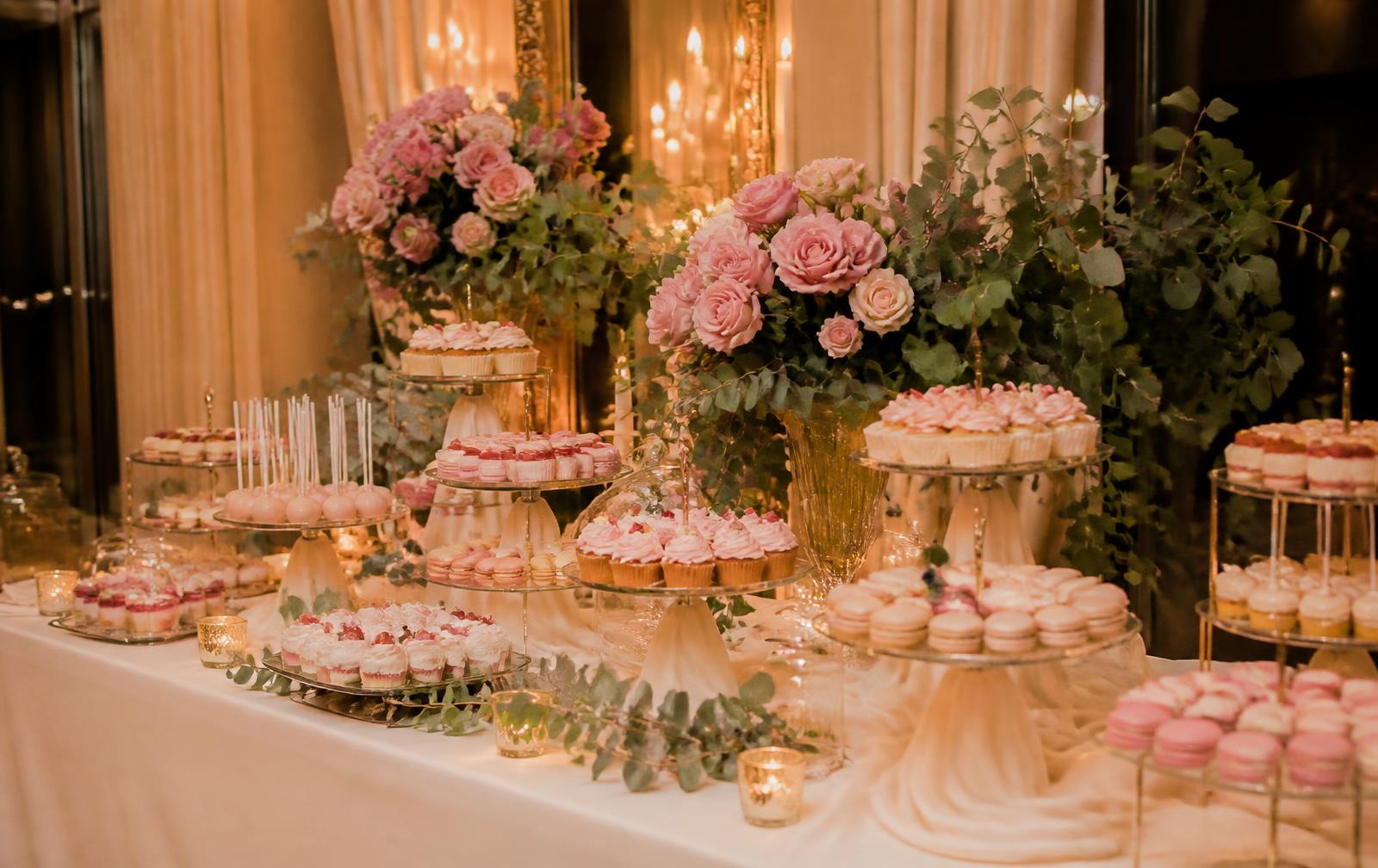 Luxury dessert table styled with tiered stands of pastel desserts and fresh roses